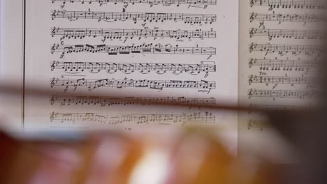 close-up of a violin focused with a sheet of musical notes in the background