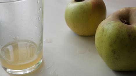 fresh apples next to a glass of cider, evoking the natural process of cider-making