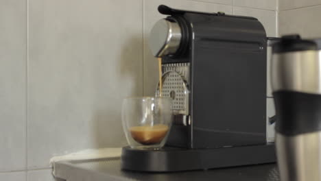 café espresso hecho de una máquina en una taza de vidrio transparente antes de ser recogido por un hombre con una camisa blanca