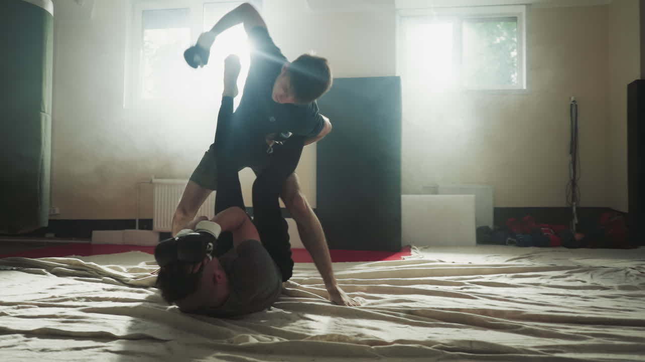 남자가 스포츠 클럽에서 파트너를 때려 얼굴을 차단합니다. 강한 싸움은 무술 체육관에서 운동하는 친구를 때립니다. 천천히 움직입니다. 손잡이 전투