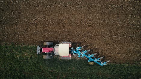 a tractor plowing a field, with a clear view of the freshly turned soil, aerial view