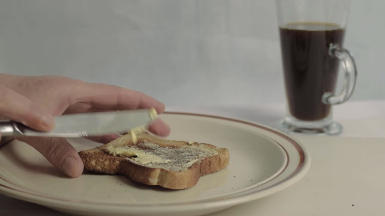 Hand spreading butter on piece of toast medium shot