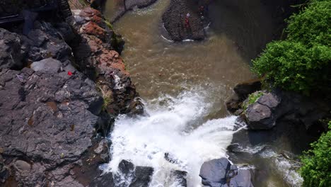 water cascade plunging into natural pool at tegenungan waterfall in bali, indonesia