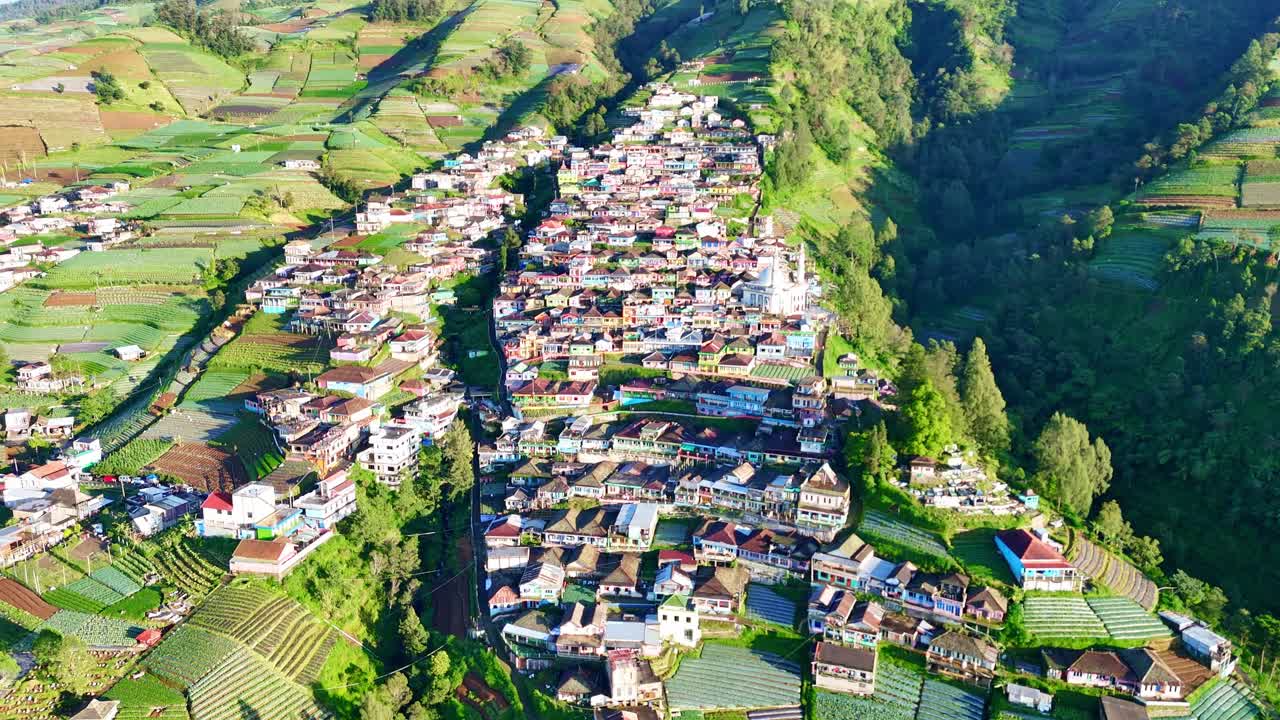 Aerial drone footage of a mountain village surrounded by terraced farms and lush green hills in the highlands of Indonesia. Nepal Van Java, Indonesia