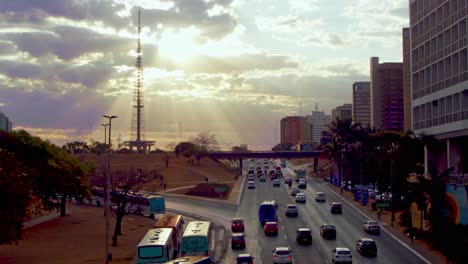 typical city traffic in brasilia, brazil at sunset with sunbeams shinning through the clouds