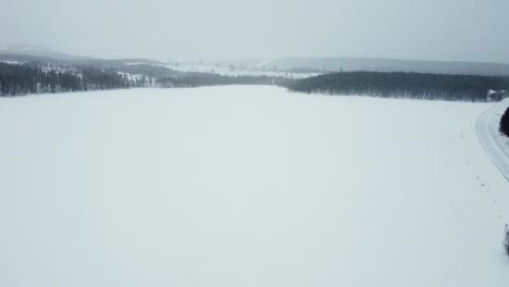 Verschneite-Straße-Mit-Wunderschönem-Blick-Auf-Die-Berge-Im-Hintergrund-Des-Polarkreises-Von-Der-Drohne-Aus