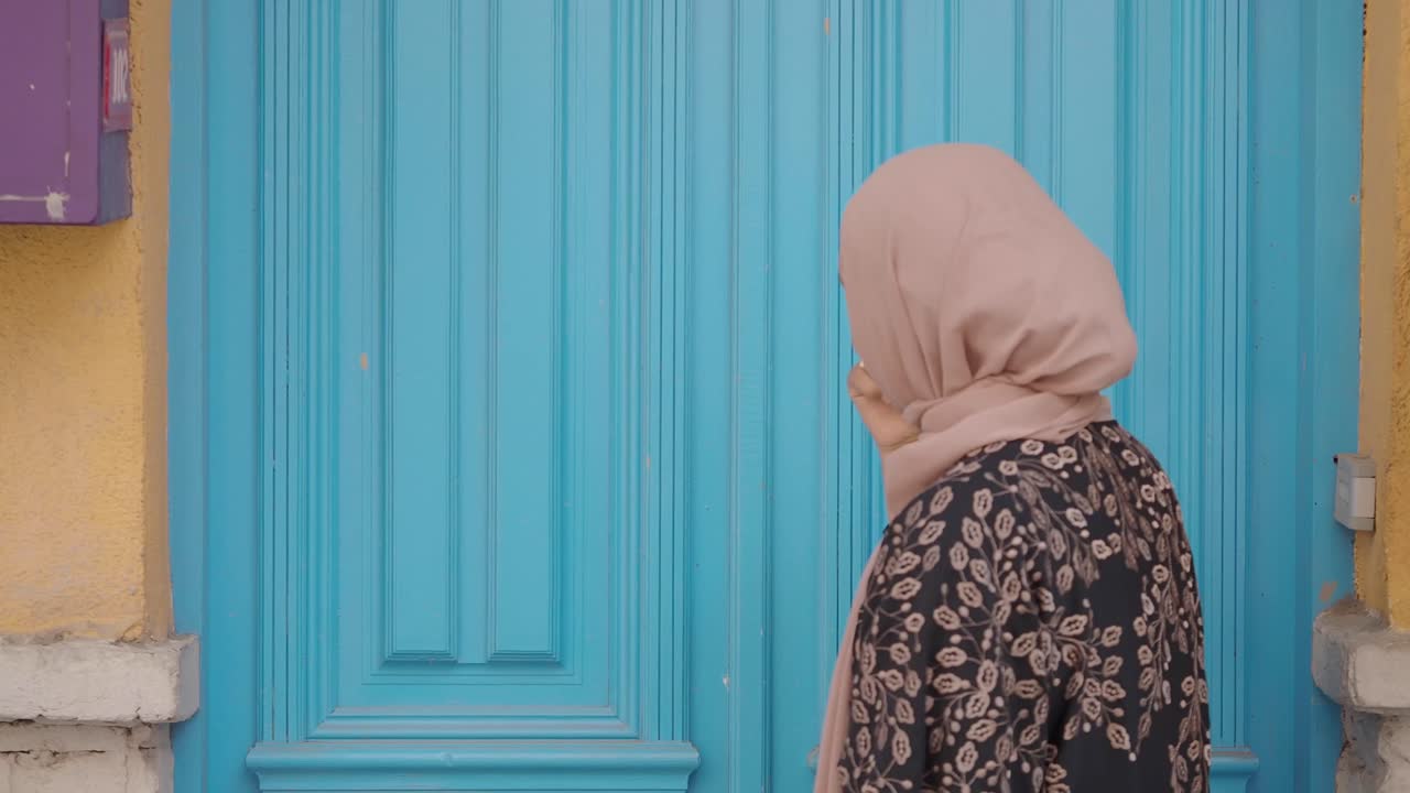 Muslim Woman Knocking on a Blue Door
