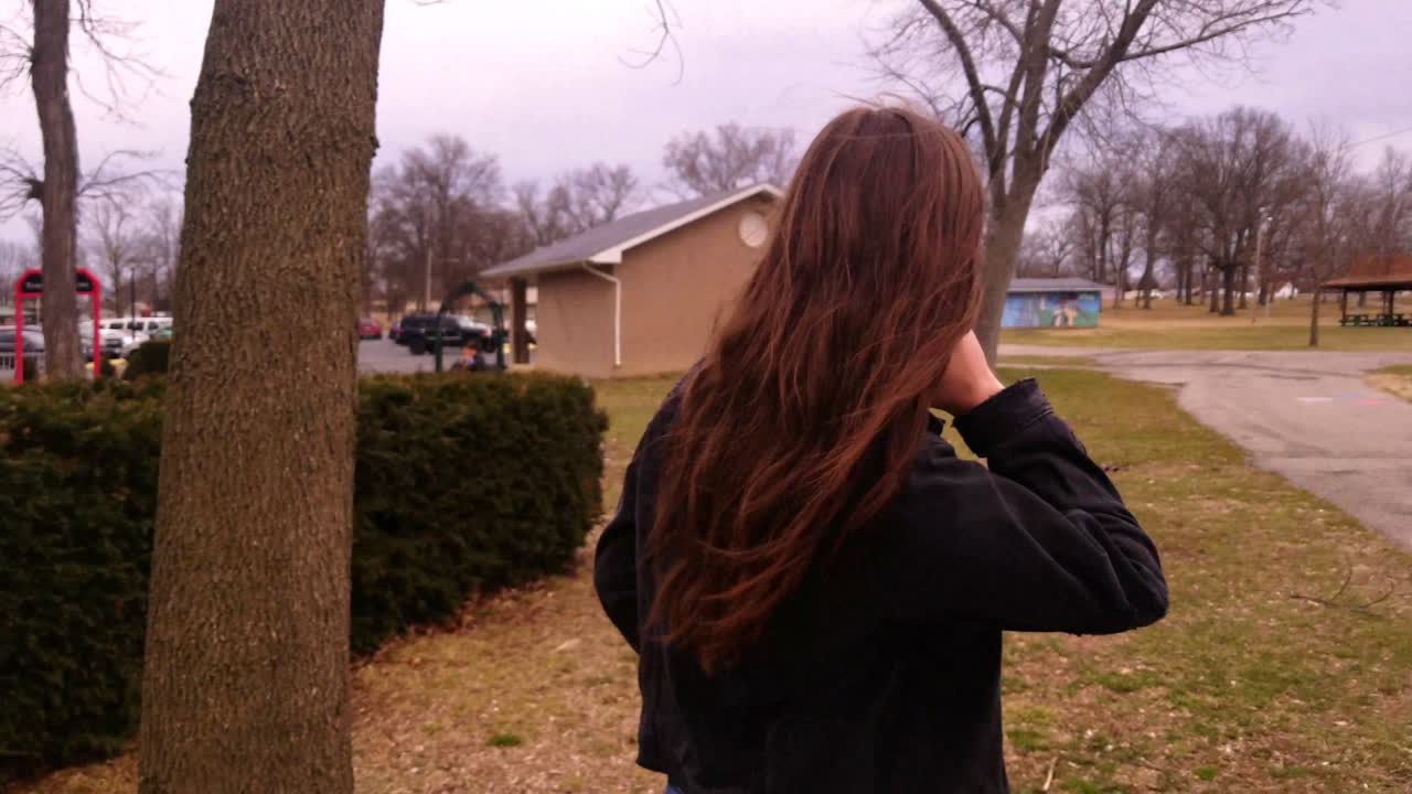 아름답고 젊고 갈색 머리의 대학생 10대가 카메라 옆을 지나 걸어가면서 머리를 넘기는 모습을 담은 4k 영상