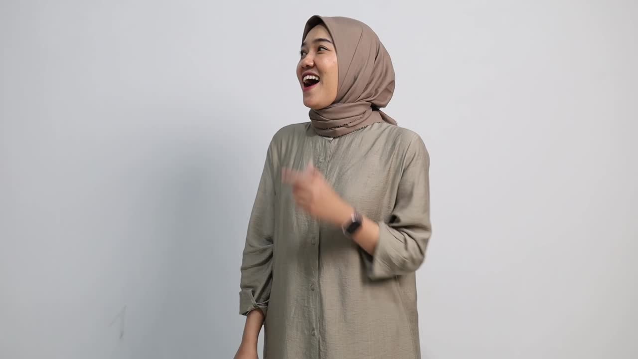 Recommending Asian muslim Woman pointing at right side, copy space. Smiling lady indicates to empty place for your advertising. Female presenting, showing something isolated on white background