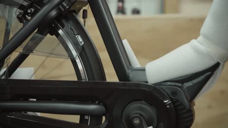 man testes the ability for a electric bicycle tire to spin as it is hanging from the ceiling in his shop