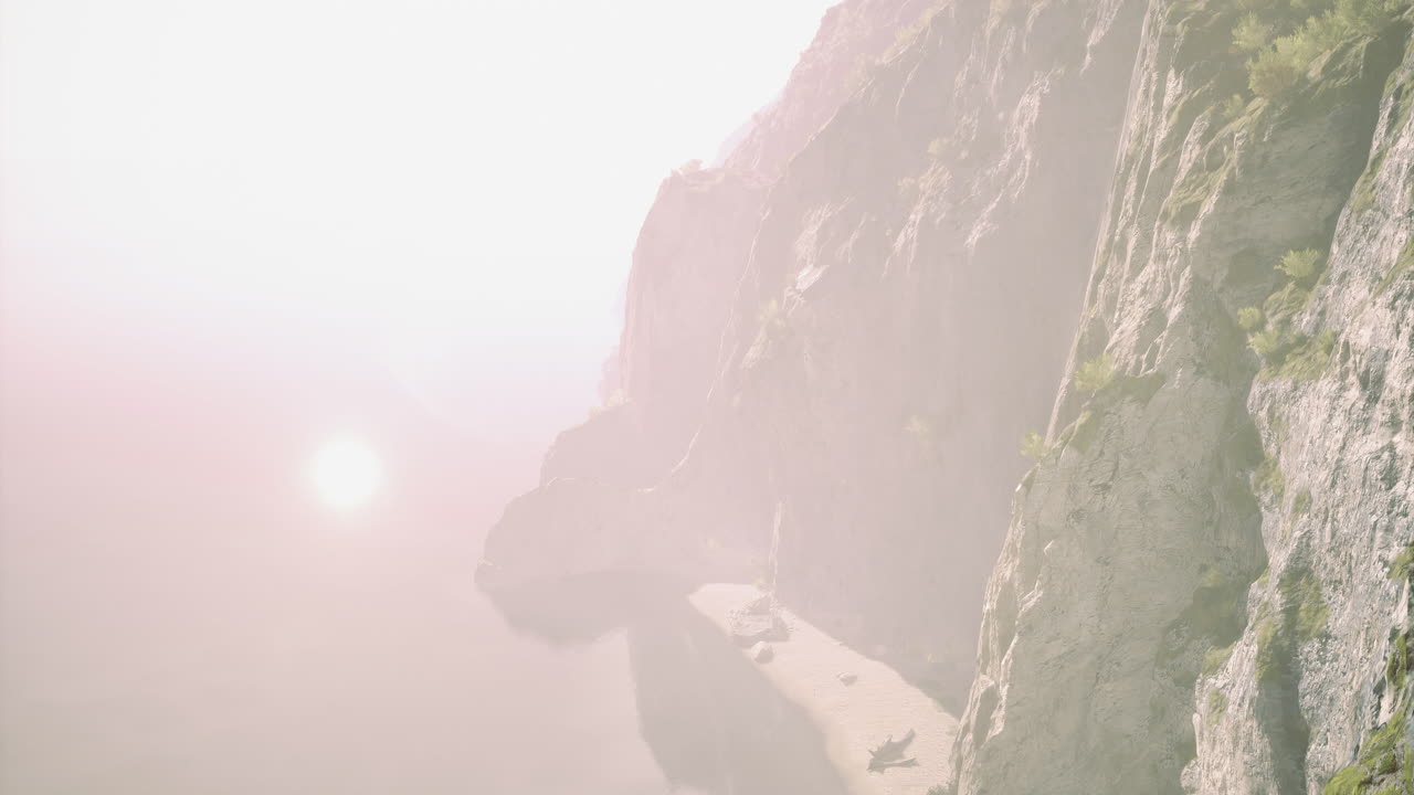 Sunrise over rocky coastline with misty atmosphere and calm water