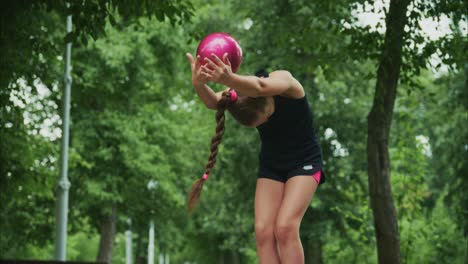 a young athlete perfects her technique in a serene outdoor environment, balancing a bright pink ball as she prepares for her next move or challenge