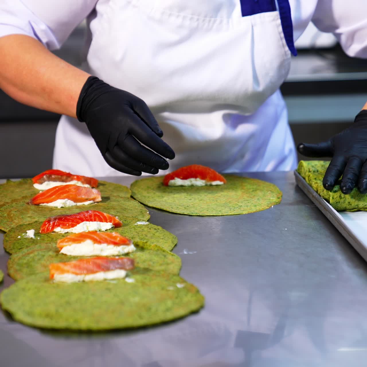 Thin pancakes with herbs are rolled with salmon and cottage cheese. Cook in black gloves puts the fish stuffing into crepes