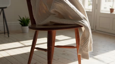 cozy white knitted sweater on a wooden chair bathed in sunlight
