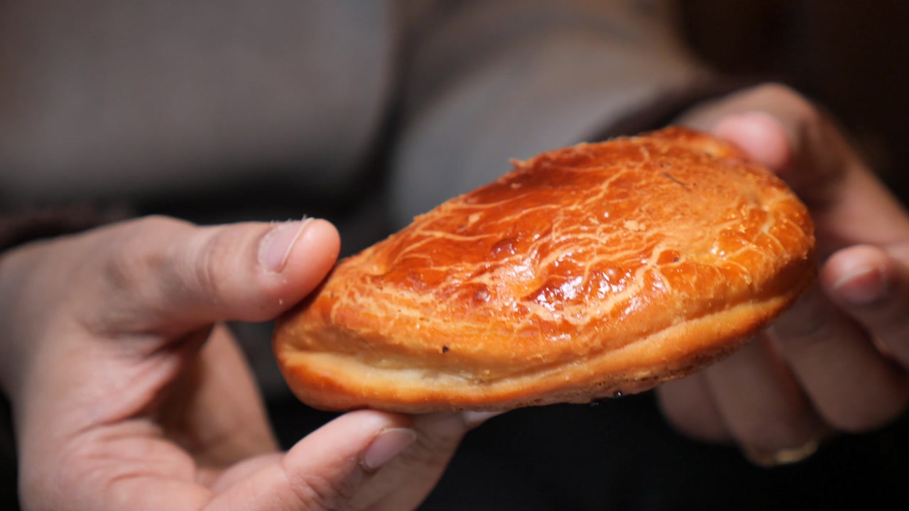 Close-up of Hands Holding a Freshly Baked Golden Pastry