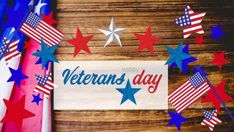 animation of veterans day text with american flags and flag elements on wood background