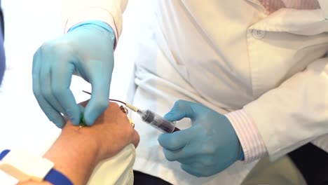 Male-doctor-taking-blood-into-a-syringe-from-a-female-patient-during-blood-donation-procedure