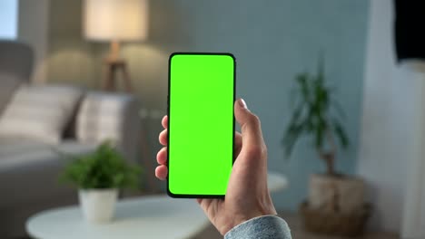 pov vista de un hombre en el teléfono con pantalla verde para el espacio de copia. chromakey mock up sin marcadores de seguimiento. niño de 20 años viendo noticias de video en el sofá de cerca. toque para hacer clic en el centro de la pantalla