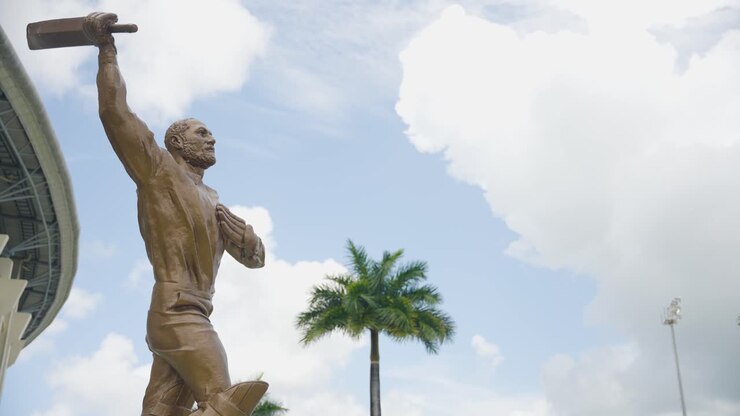 Panning shot from Viv Richards Stadium in Antigua in the Caribbean to reveal a statue of him, raising his cricket bat in the air