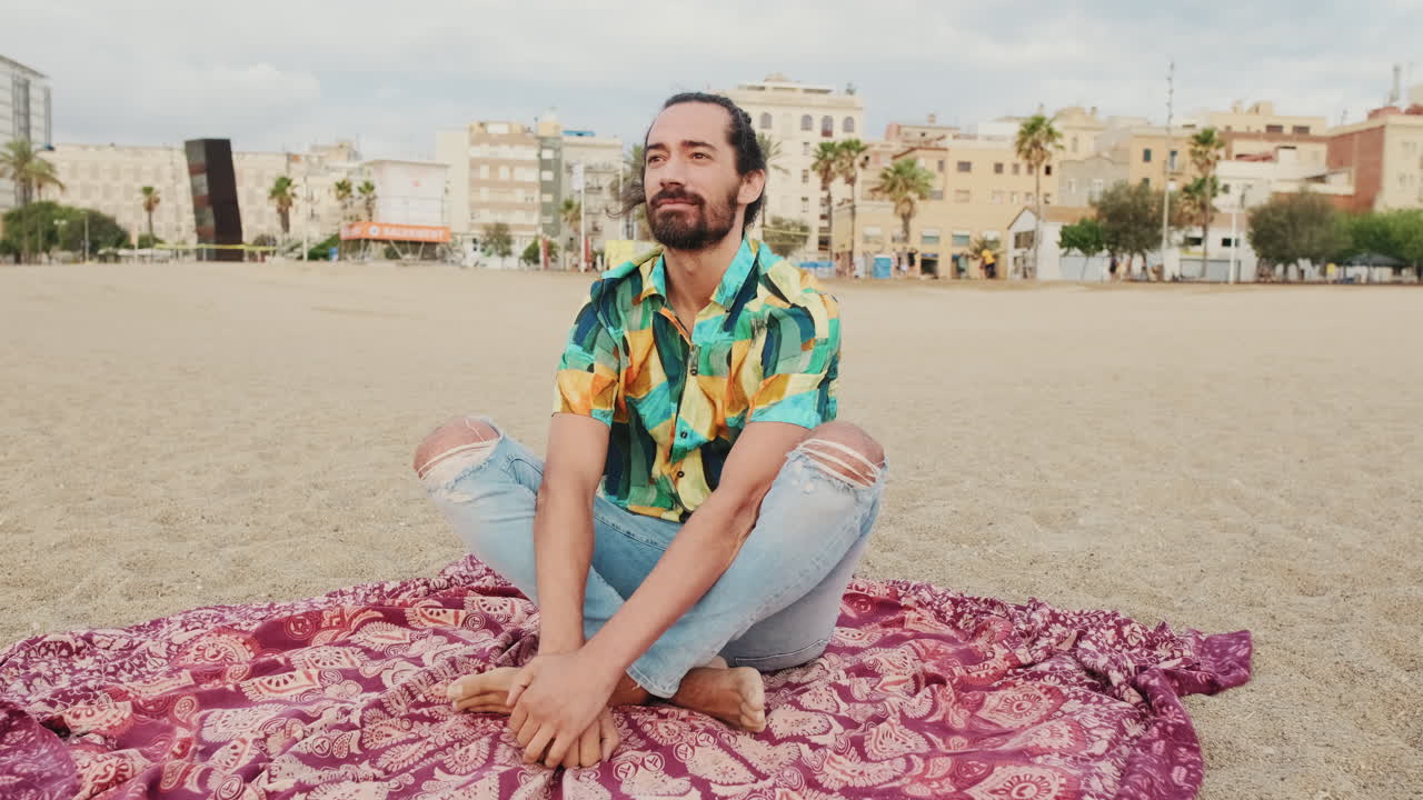 Hombre sentado en la playa con paisaje urbano