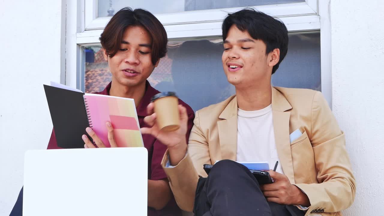 Cheerful Young students collaborate on homework while drinking coffee break at yard