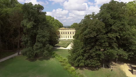 Flying-in-a-park-with-a-pond-and-middle-ages-castle-in-France.-Day-time-aerial