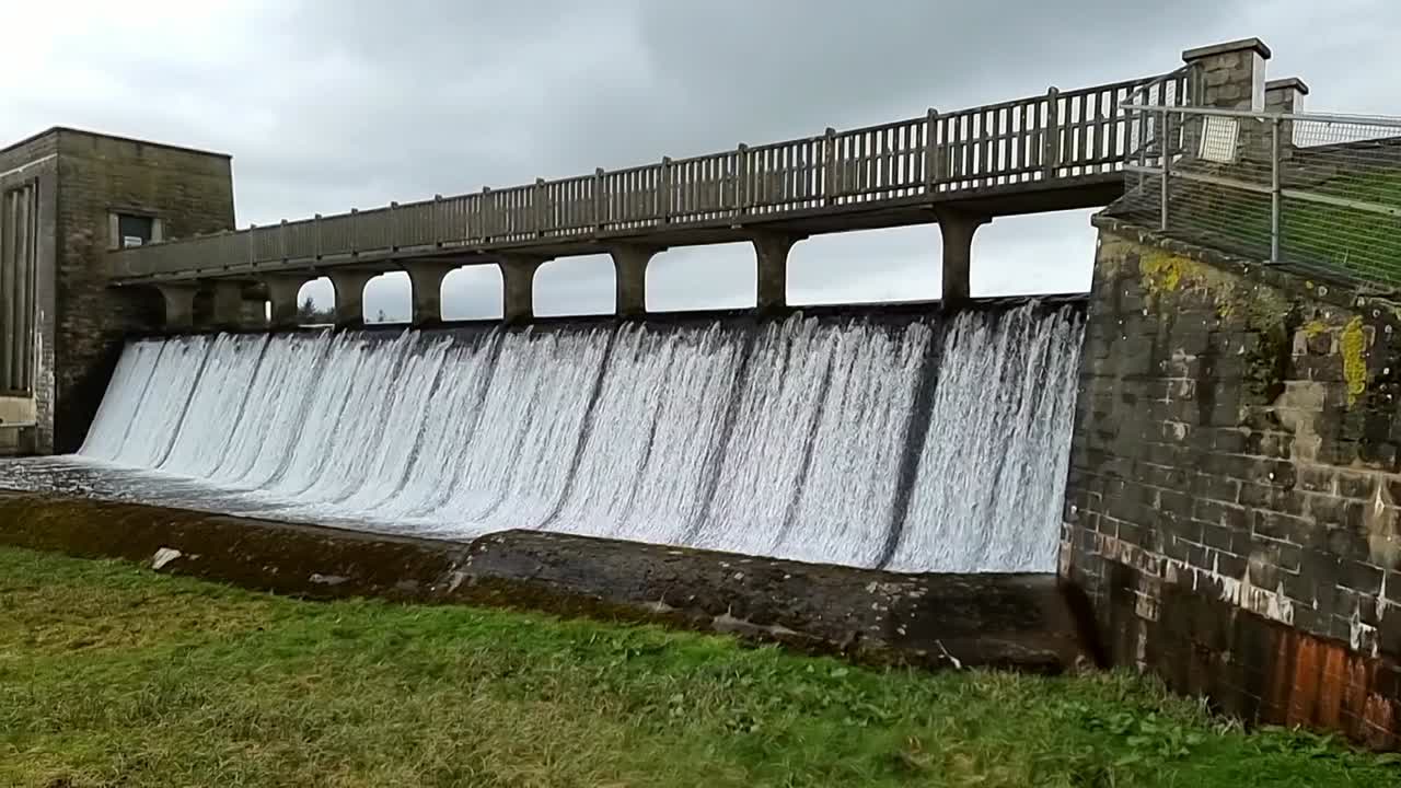 Cefni dam concrete barrier gate pouring slow motion water overflow from Llangefni, Anglesey reservoir lake