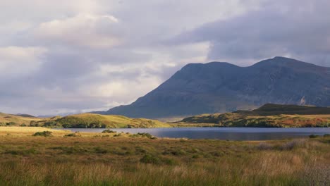 shadows from drifting clouds move across the mountains and moorland at loch stack in the scottish highlands, creating dramatic light over the rugged landscape