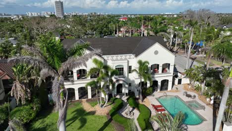 luxury mansion or villa with swimming pool in garden during sunny day. palm trees in well-manicured garden. descend drone shot. sunny day in summer. sarasota, florida.