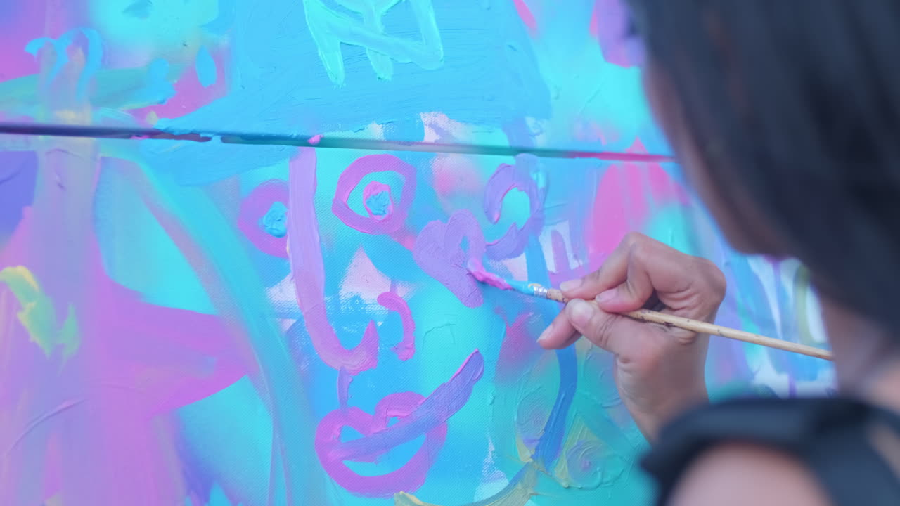Primer plano de una mujer pintando un corazón morado en un gran lienzo de tela en un parque público
