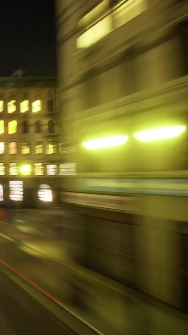 Scena notturna di una strada trafficata con luci sfocate ed edifici in città.