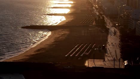drone footage, shooting tourists at boardwalk at quareira, algarve, portugal during sunset - backlit