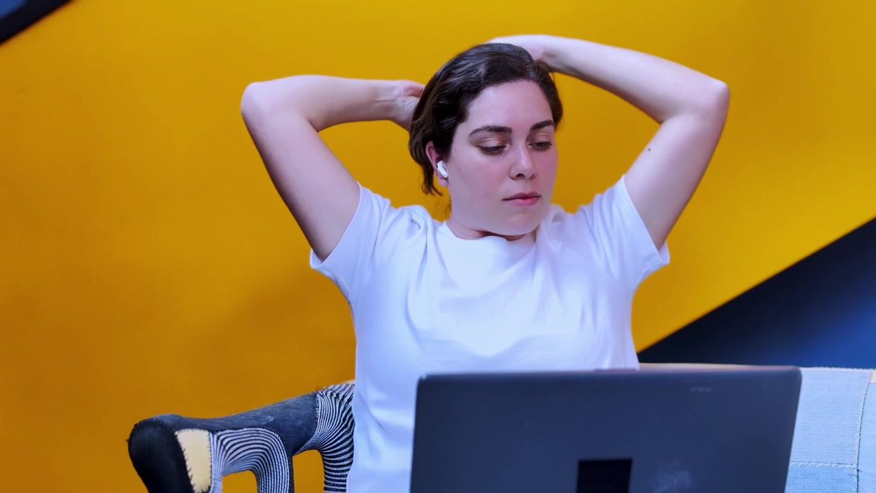 Woman stretching while working remotely on laptop