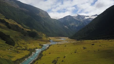 an ascending drone shot of a river in a deep valley in new zealand