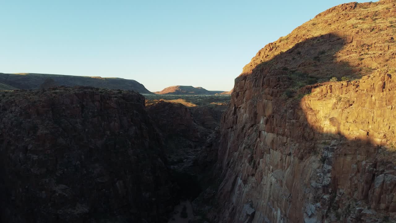 vista aérea cinematográfica dolly volando sobre una exuberante garganta del desierto entre dos acantilados a la hora dorada en el parque riemvasmaak en sudáfrica cerca de namibia
