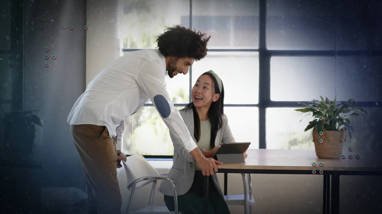 Man leaning over table reaching tablet guiding woman tapping for business as passive Xs showing