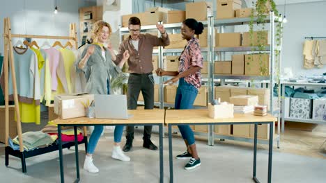 Diseñadoras-De-Ropa-Y-Sastre-Bailando-En-Un-Taller-Divirtiéndose,-Sintiéndose-Feliz-Y-Celebrando-La-Apertura-De-La-Tienda