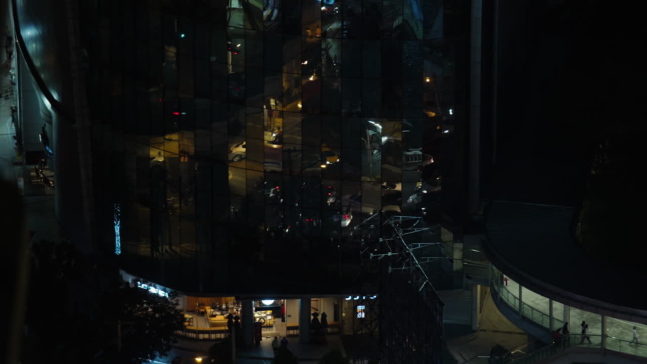 動きの速い忙しい都市、繁華街の夜のファサードの反射とバンコクの通りを移動する車、繁華街を反映する鏡の建物