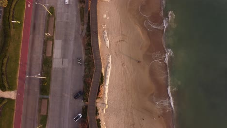 Toma-Aérea-De-Arriba-Hacia-Abajo-De-La-Playa-De-Arena,-El-Océano-Y-Los-Automóviles-En-La-Carretera-En-Punta-Del-Este,-Uruguay