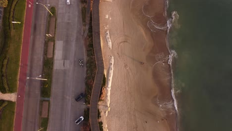 toma aérea de arriba hacia abajo de la playa de arena, el océano y los automóviles en la carretera en punta del este, uruguay