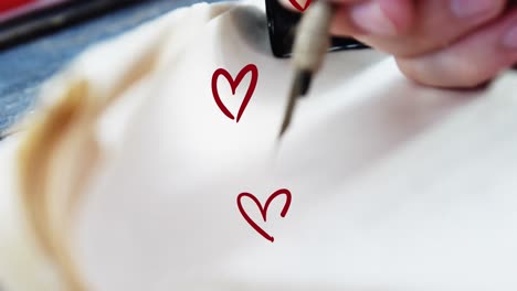 animation of hearts over hand writing in notebook