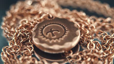 a detailed crispy macro shot of a golden medallion necklace, flying bird in the middle of the sun symbol, on a rotating stand, mirror reflection, studio lighting, 4k video