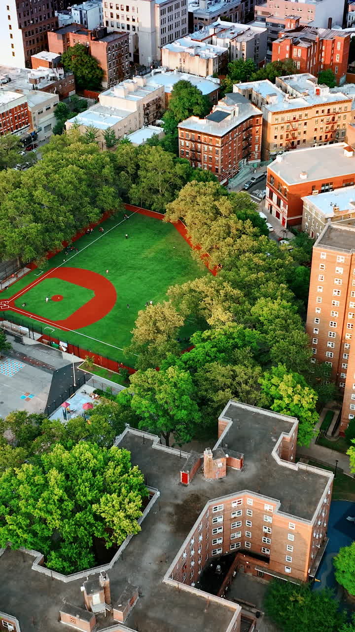 Green residential area with multistoried buildings of unusual design. Stadium for basketball games in the neighborhood. New York panorama. Top view. Vertical video