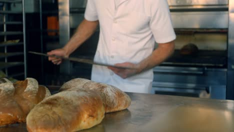 Baker-removing-freshly-baked-bread-bun-from-the-oven-4k