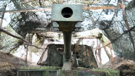 a powerful close-up shot looking directly down the barrel of a pzh 2000 howitzer. the german-made artillery is hidden under camouflage netting on the ukrainian front