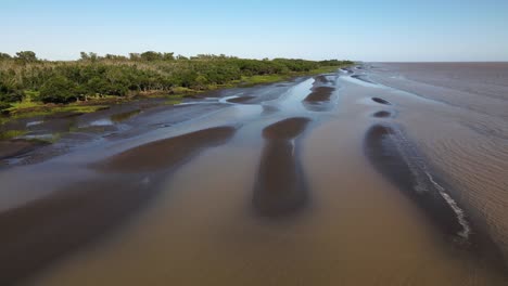 Toma-Aérea-De-Olas,-Bancos-De-Arena-Y-Naturaleza-Verde-Por-El-Río-De-La-Plata