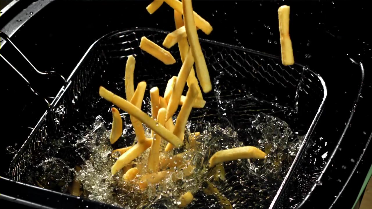 Golden French Fries Splashing into Hot Deep Fryer Oil
