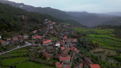 orbiting shot of scenic ermida village on lush valley with foggy mountains, peneda-gerês