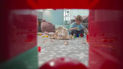 cute toddler plays with plastic blocks after building house