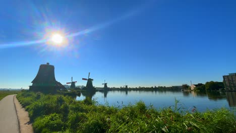 sun shining bright at dutch mills and green landscape by lake at zaanse schans